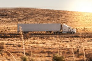 a white semi truck driving down a rural road